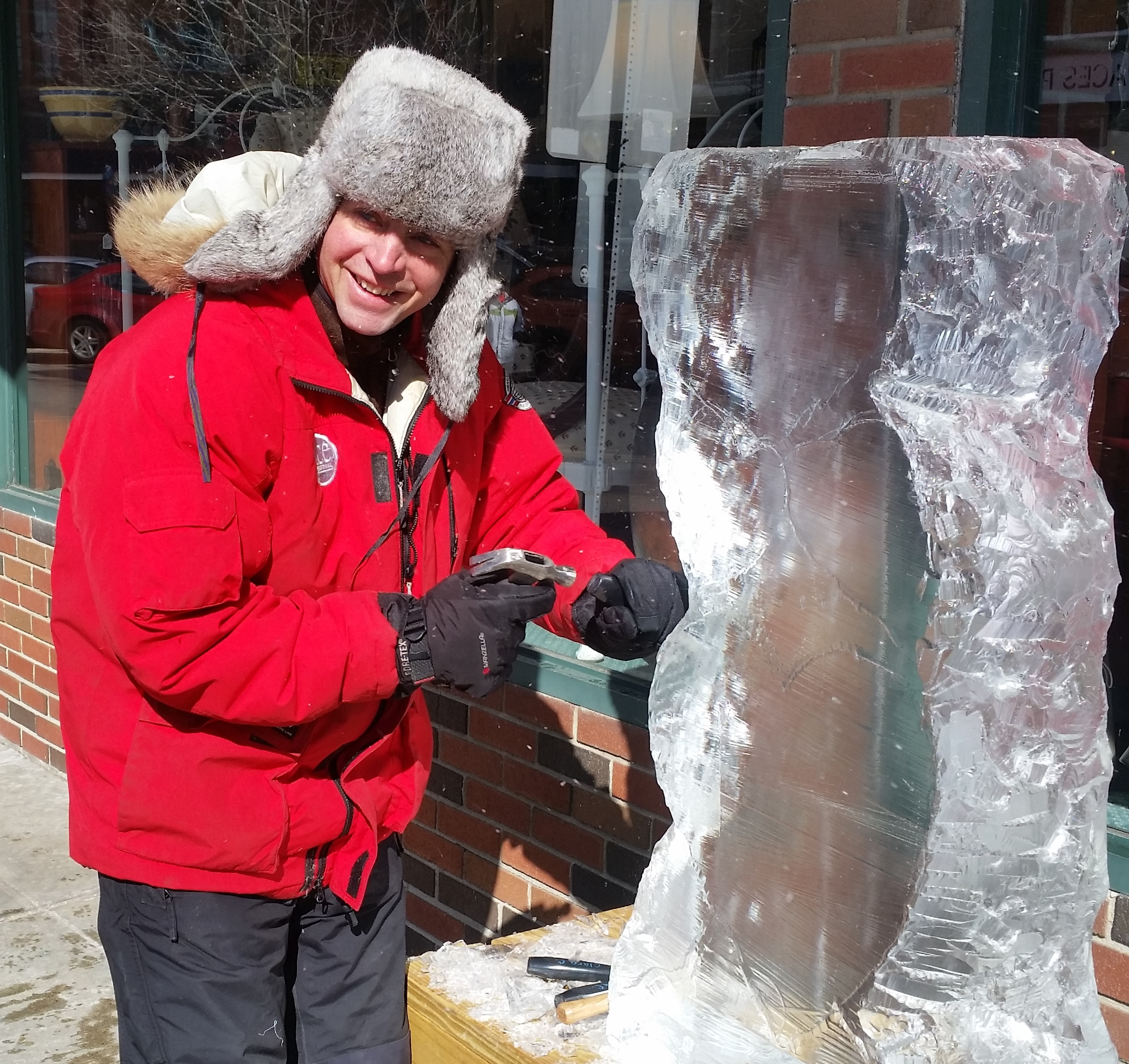 Bundled up ice carver in a red jacket working outdoors in winter weather