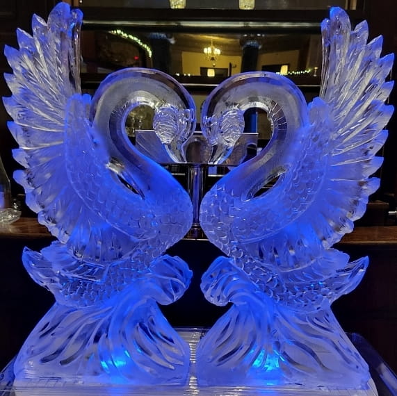 Majestic double swan ice sculpture glowing with intense deep blue LED lights