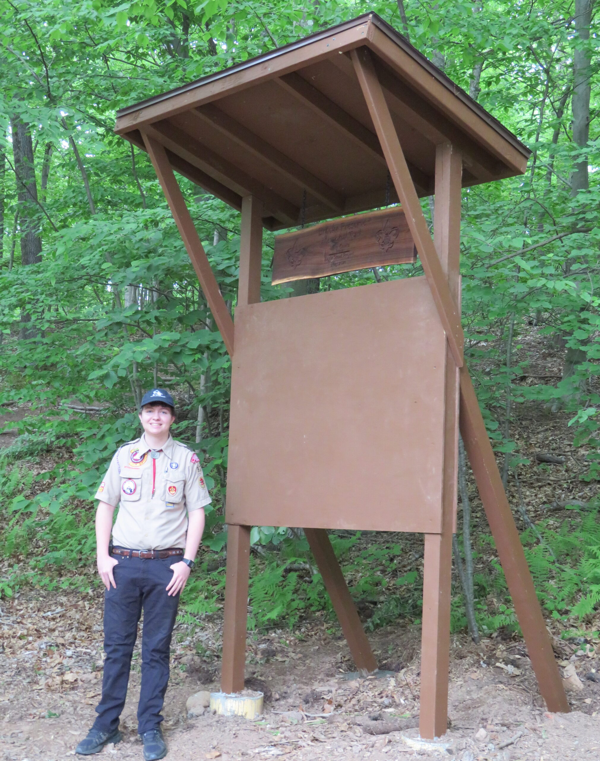 Park ranger standing next to an outdoor wooden park informational sign