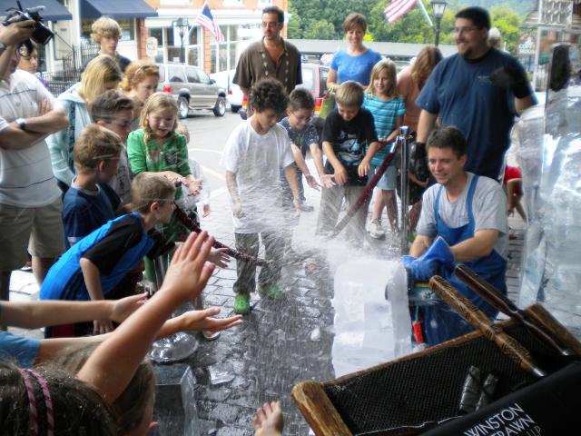 Crowd of people watching a live ice carving demonstration on a town street