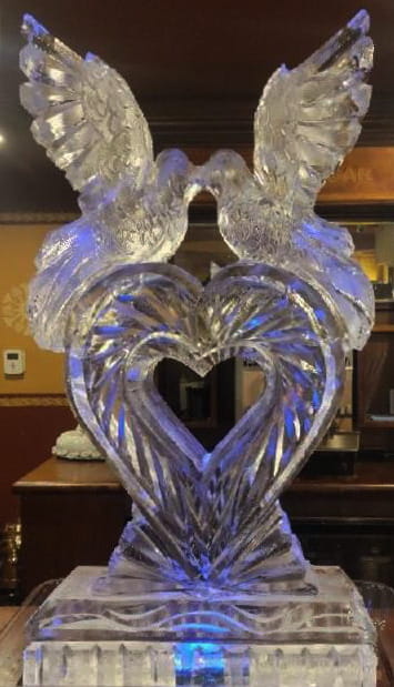 Elegant interlocking wedding swans ice sculpture under warm indoor lighting