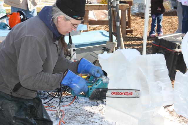 Artisan wearing thick safety gloves working with tools on an ice carving base