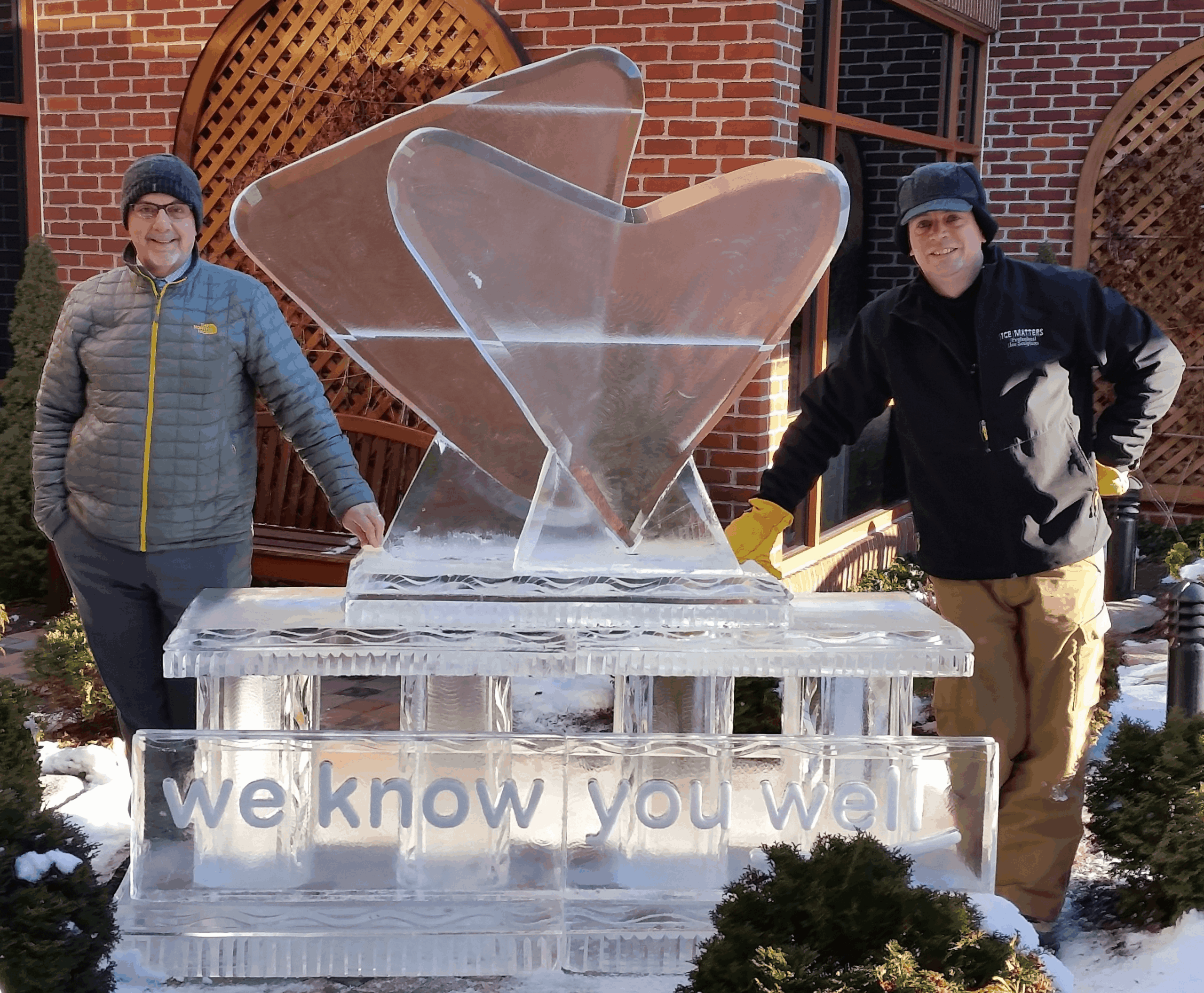 Large custom outdoor ice sculpture of abstract wings with people standing nearby