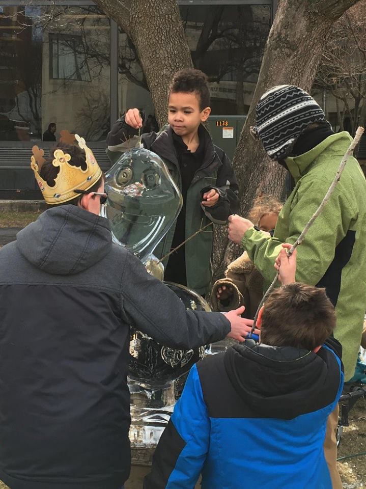 Group of kids and adults examining an outdoor winter ice installation