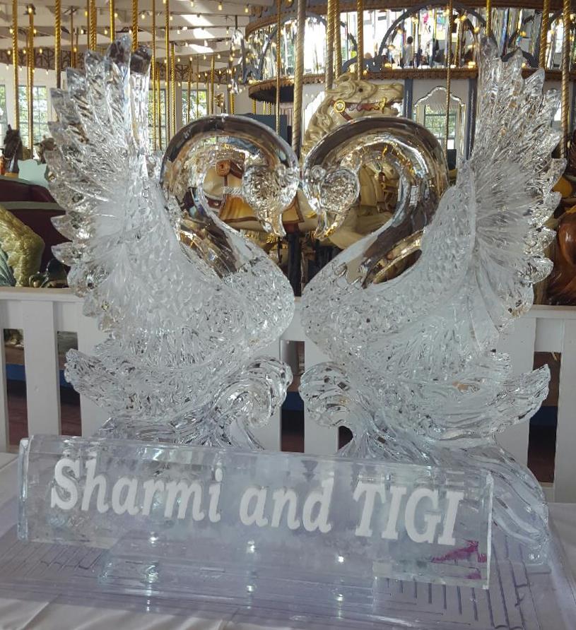 Symmetrical double swan ice carving displayed on a banquet food table