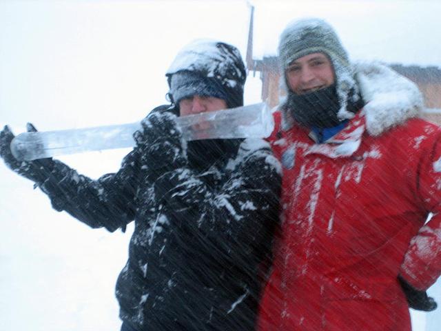 Two people using a large crosscut saw to cut ice blocks outdoors in winter