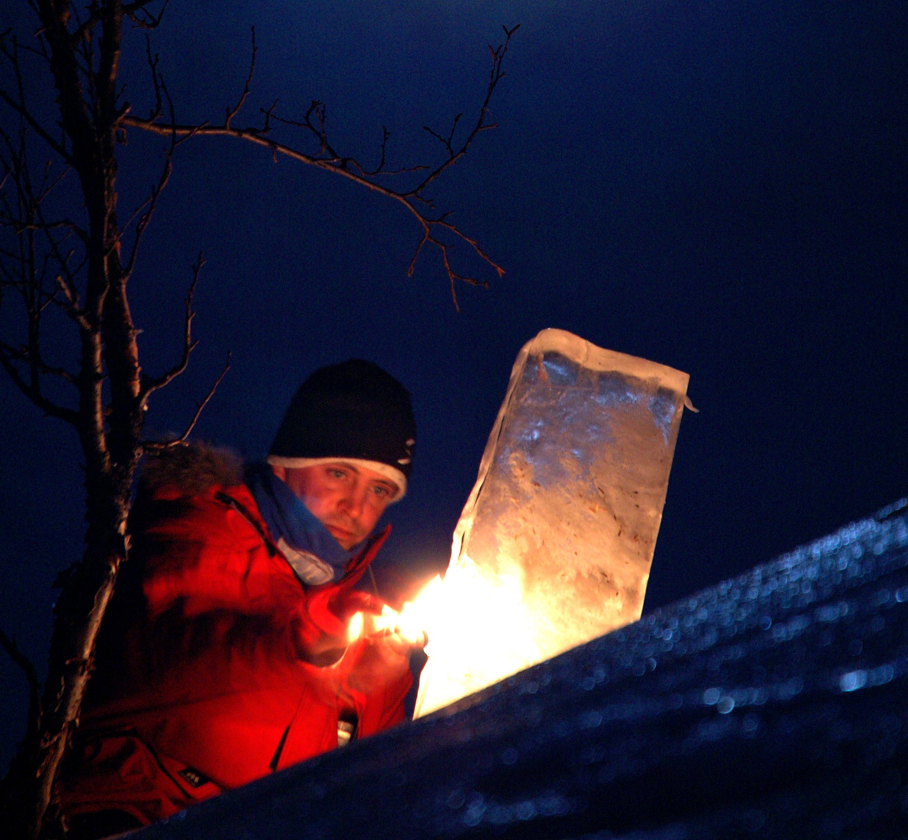 Ice carving professional working at night under orange ambient event lighting
