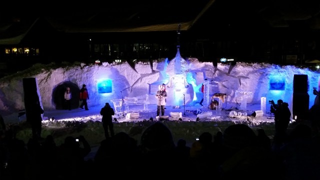 Live musical concert performance taking place inside an illuminated ice palace venue