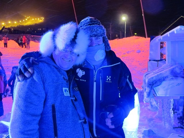 Two winter festival team members smiling and hugging inside an illuminated ice room