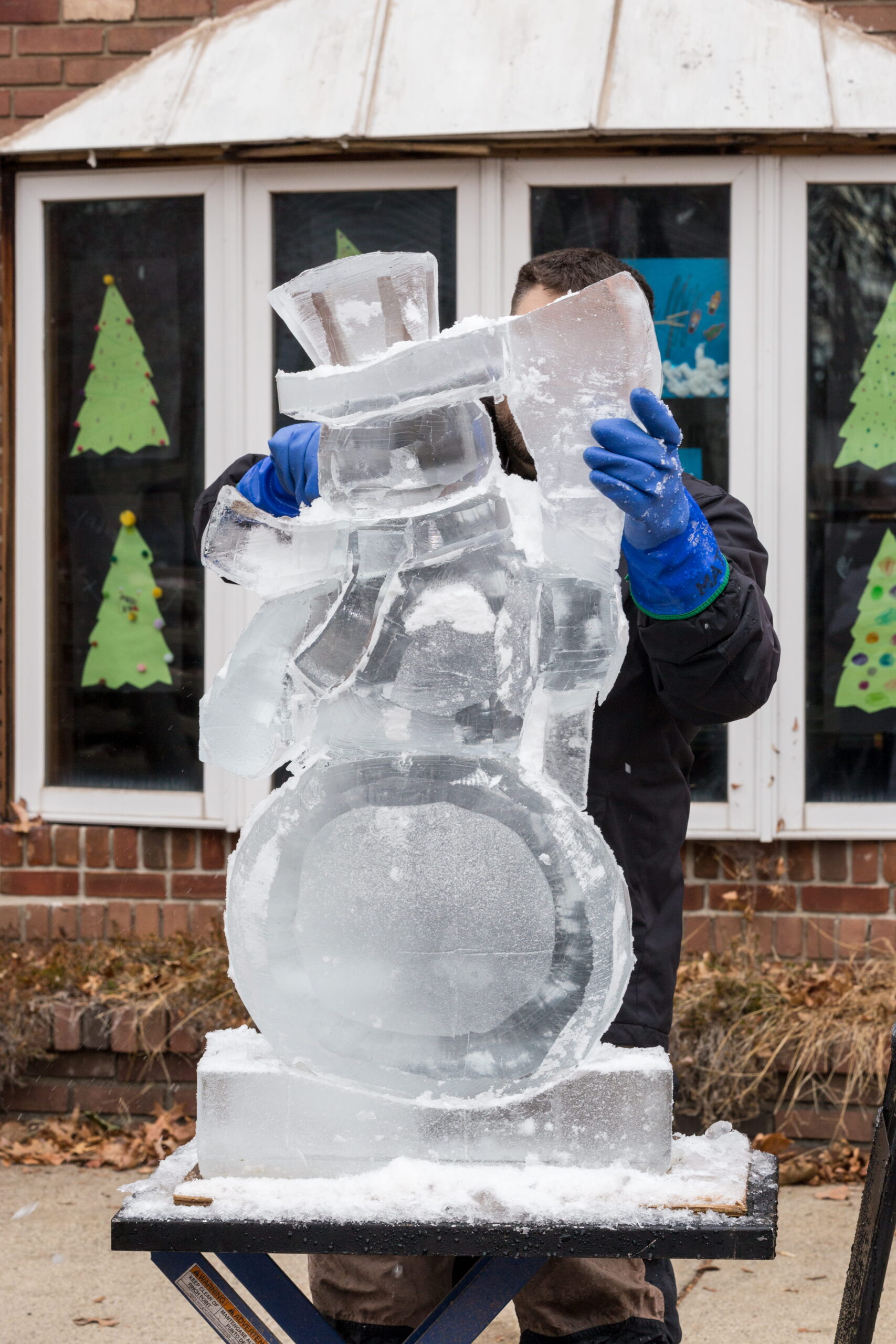Ice carver adjusting a winter themed snow and ice snowman block setup