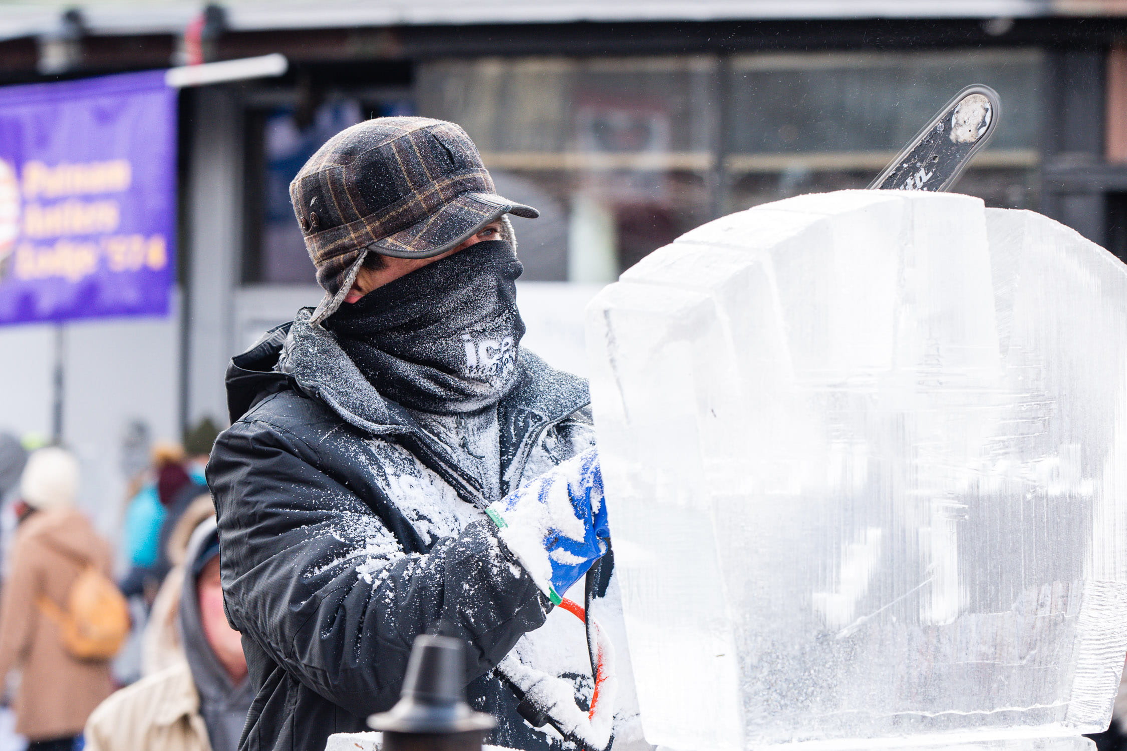 Bundled-up ice carver working outside on a large winter sculpture project