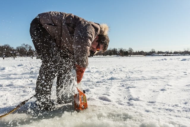 Worker adjusting heavy snow blocks or ice structures at a winter festival site