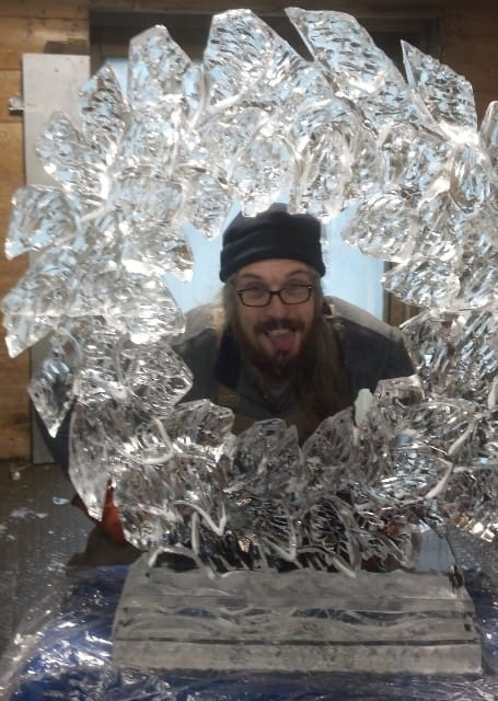 Man smiling behind a custom cutout ice sculpture frame for photo opportunities