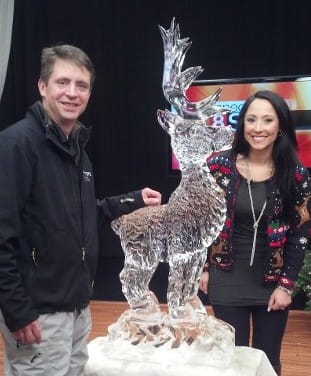 A man and woman posing next to a custom deer or stag ice sculpture