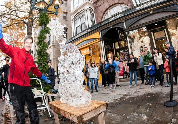 Tall ice sculpture column displayed on a historic brick town street corner