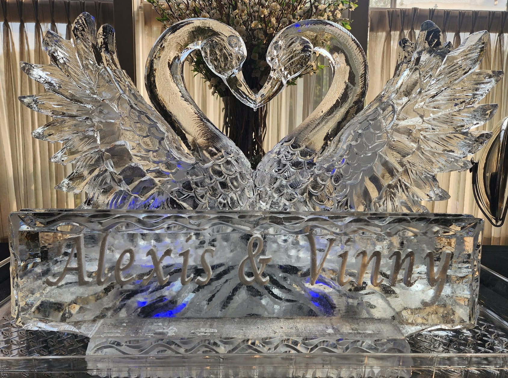 Beautifully detailed clear ice carving of kissing swans at a grand buffet