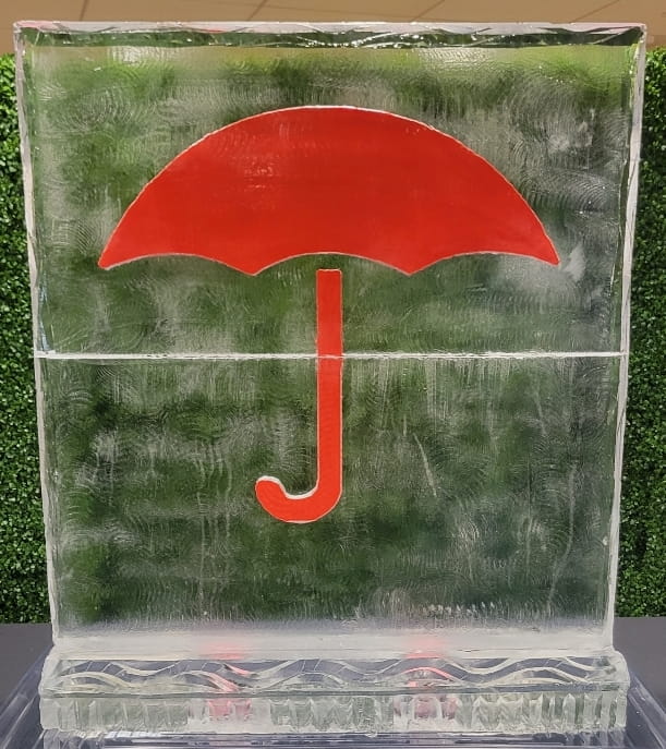 Custom clear ice sculpture block featuring a prominent red umbrella design