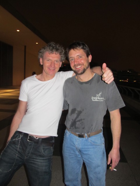 Two men smiling together inside a venue next to an ice sculpture display