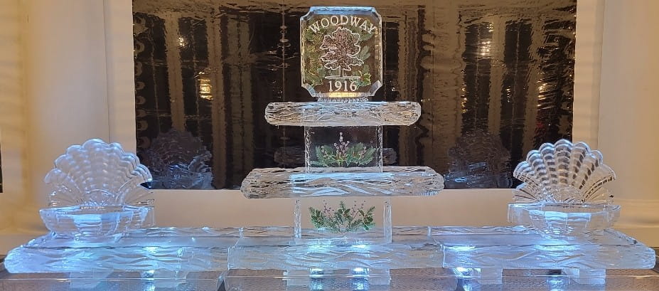 Ice matters - festive holiday greens frozen into supports and topper of tiered tray with snowfilled logo and open shell on each end of 120 inch base tray