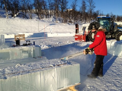 Festival staff working with a snow clearing tool at an outdoor ice sculpture site
