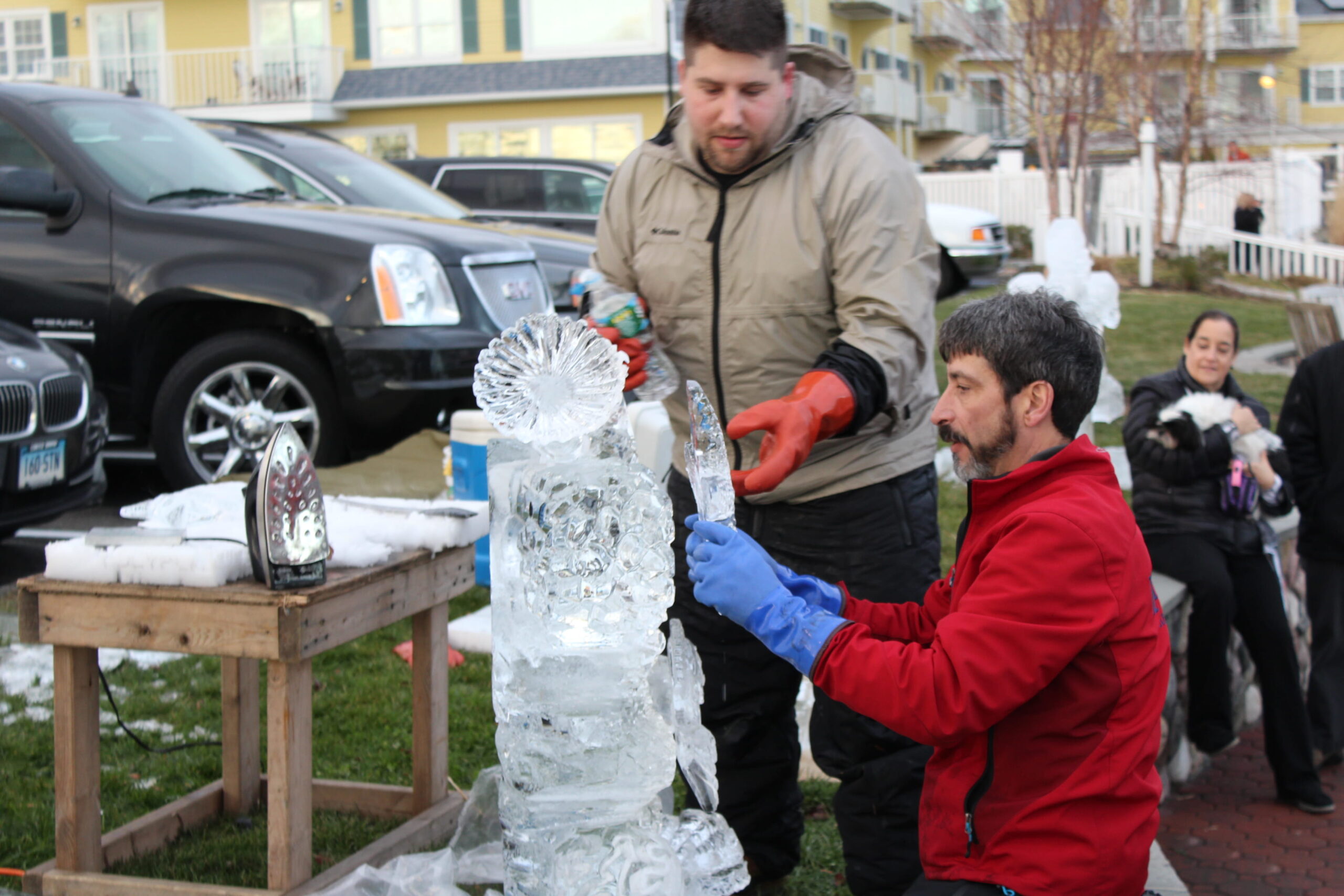 Two event team members setting up an ice display next to a parked car