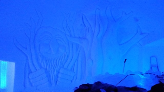 Textured details of a massive abstract ice wall carving illuminated in blue