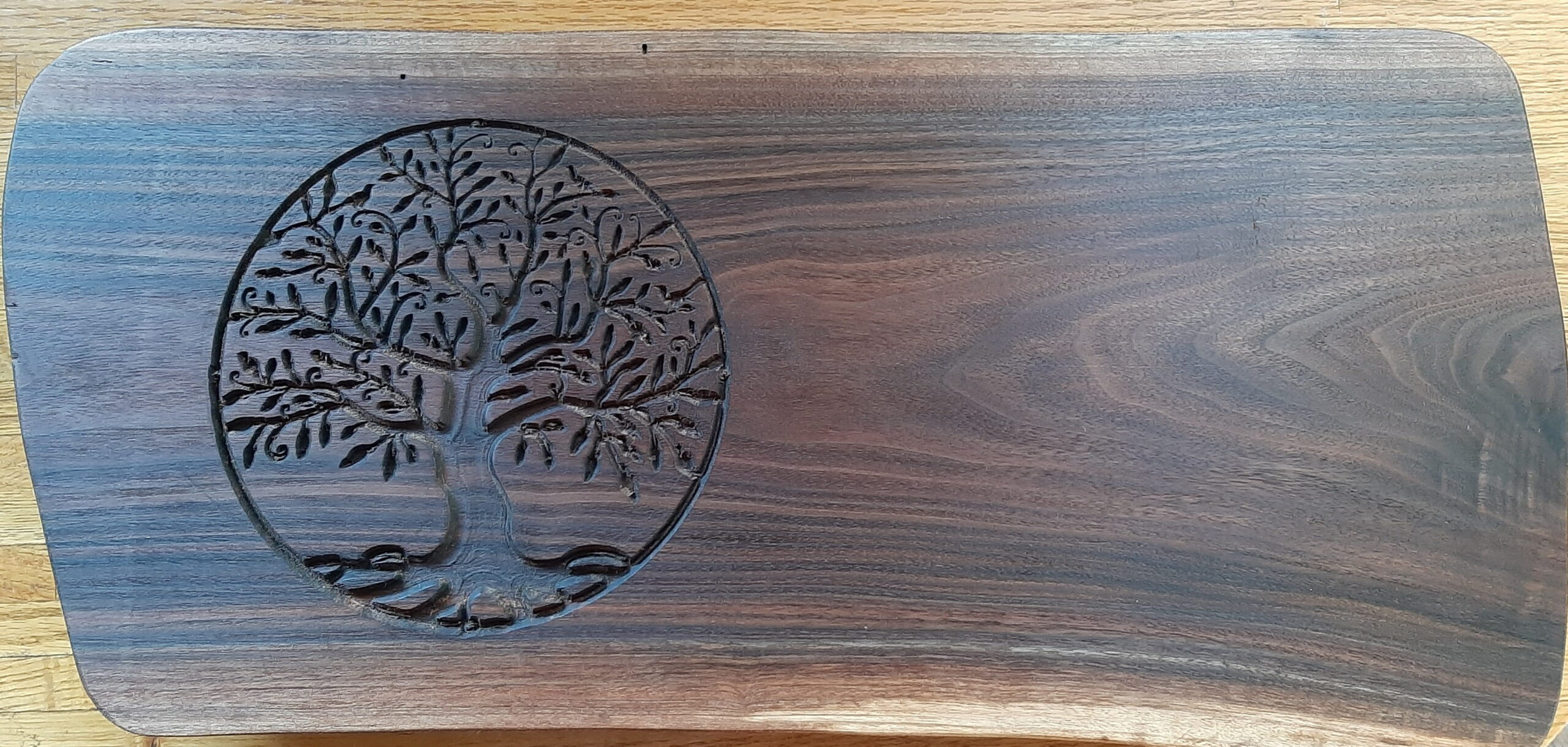 Intricate tree of life circular carving on a dark walnut wood board