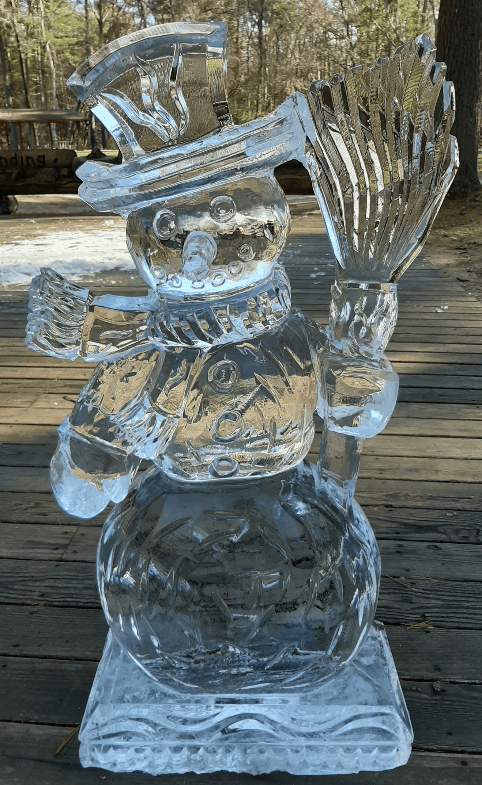 Whimsical clear ice sculpture of a snowman sitting down outdoors