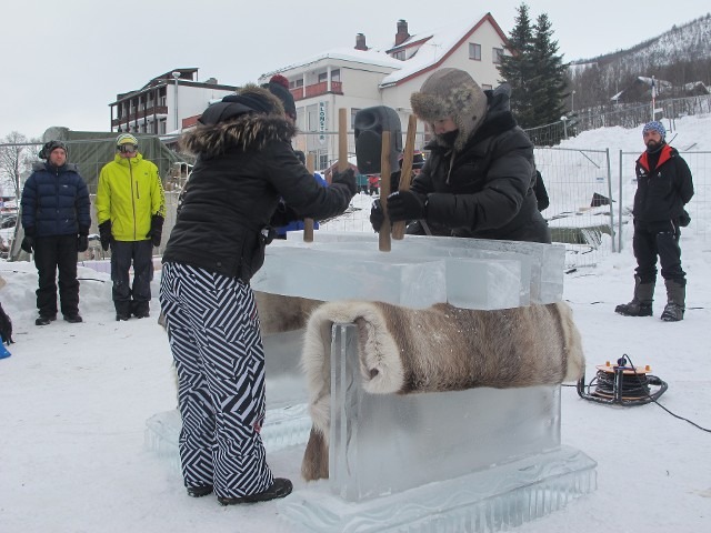 Outdoor winter event scene with attendees gathered around a structural snow base