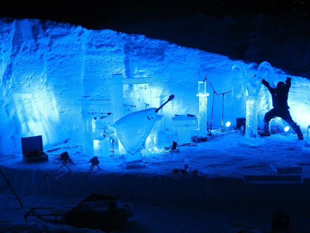 Wide view of an intricate multi piece ice display illuminated inside a snow fort
