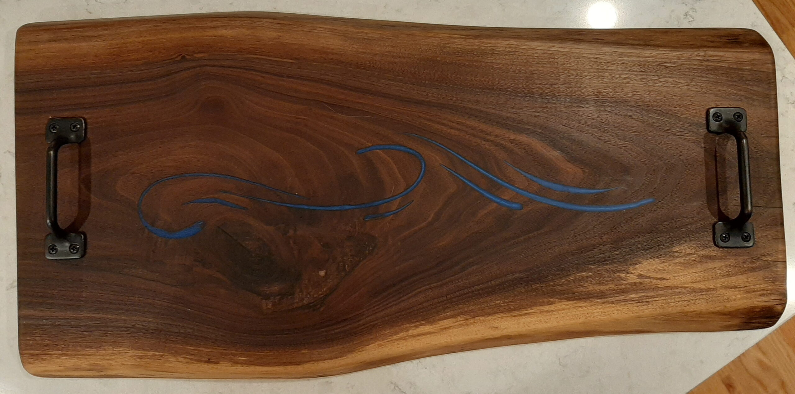 Live edge wood slab art piece with a flowing blue epoxy resin river inlay