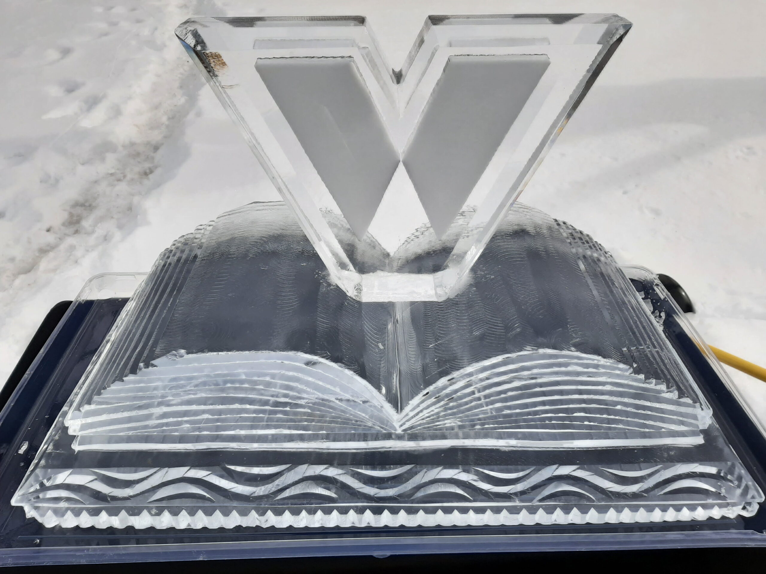 Modern open book ice carving with a large initial logo on top