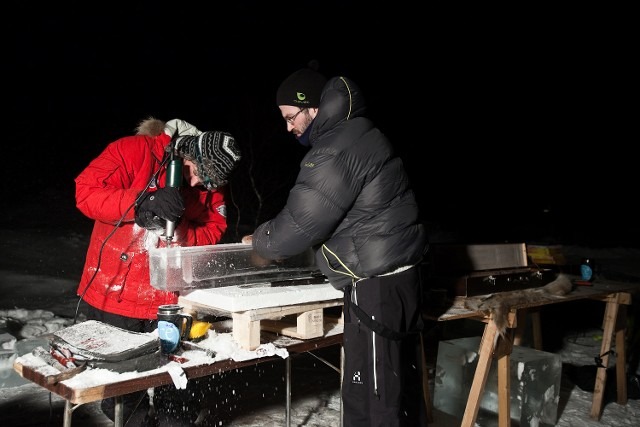 Sculptor using precision power tools to carve a custom ice block structure