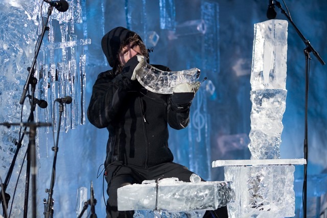 Musician blowing into an ice horn instrument during a winter performance