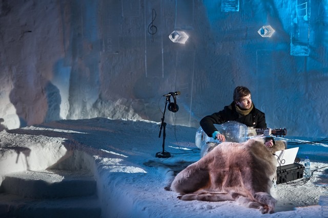 Musician setting up audio equipment inside a custom carved ice room cave