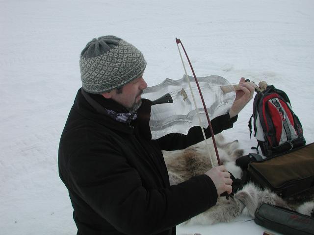 Musician playing a violin next to an intricate ice structure sculpture